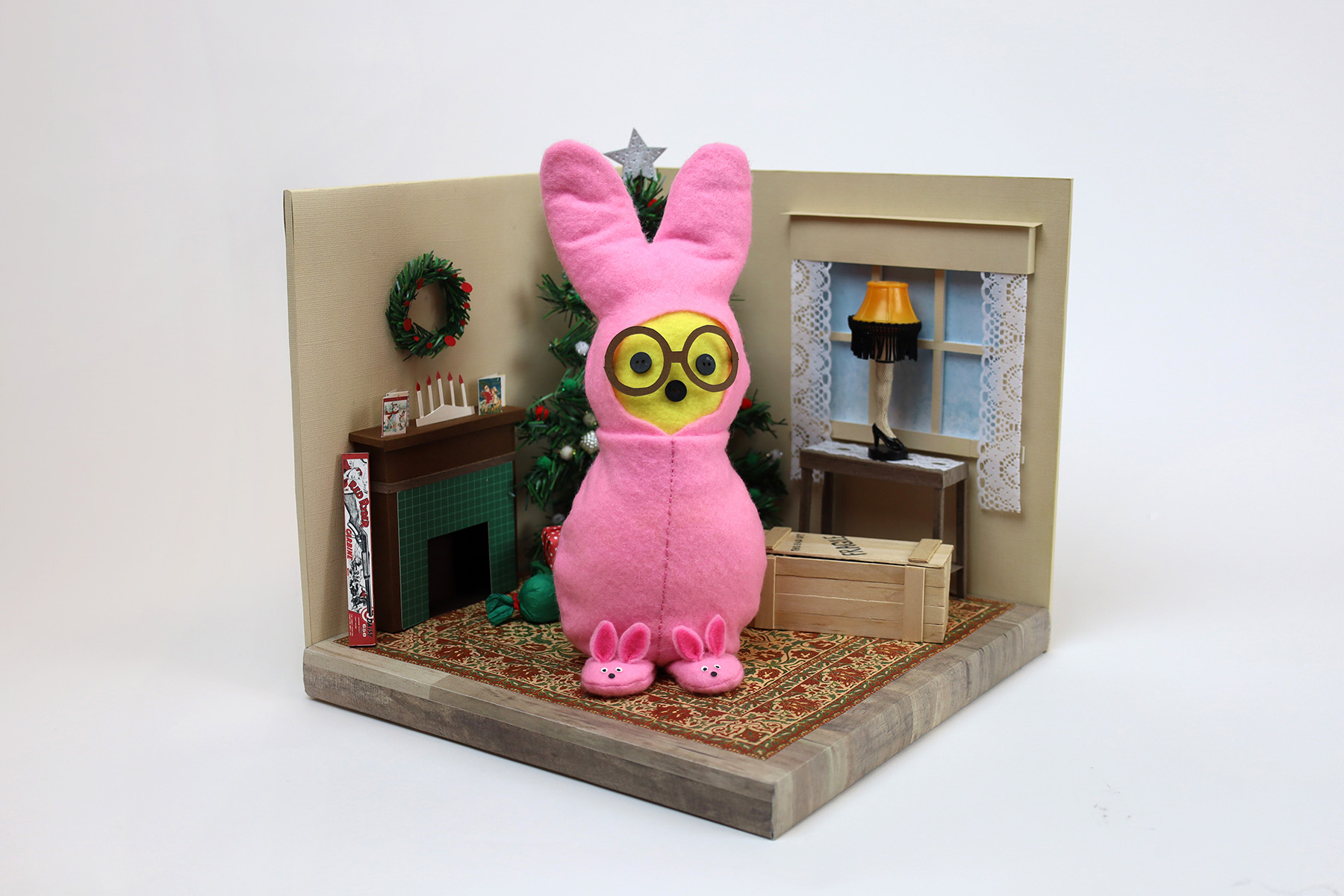 Julie Serbiak, He Looks Like a PEEP Nightmare! A bunny peep wears a onesie and stands in front of a Christmas tree, fireplace and heel lamp.