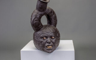 A circular ceramic vessel with many engravings, including a very angry and scared face.