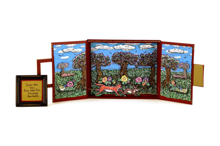 A box opens up into a trifold with a fox chasing a rabbit through a forest.